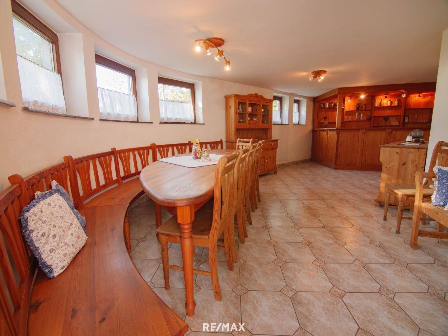 Rustikaler Essbereich mit Holztisch, eingebauter Sitzbank und gefliestem Boden.