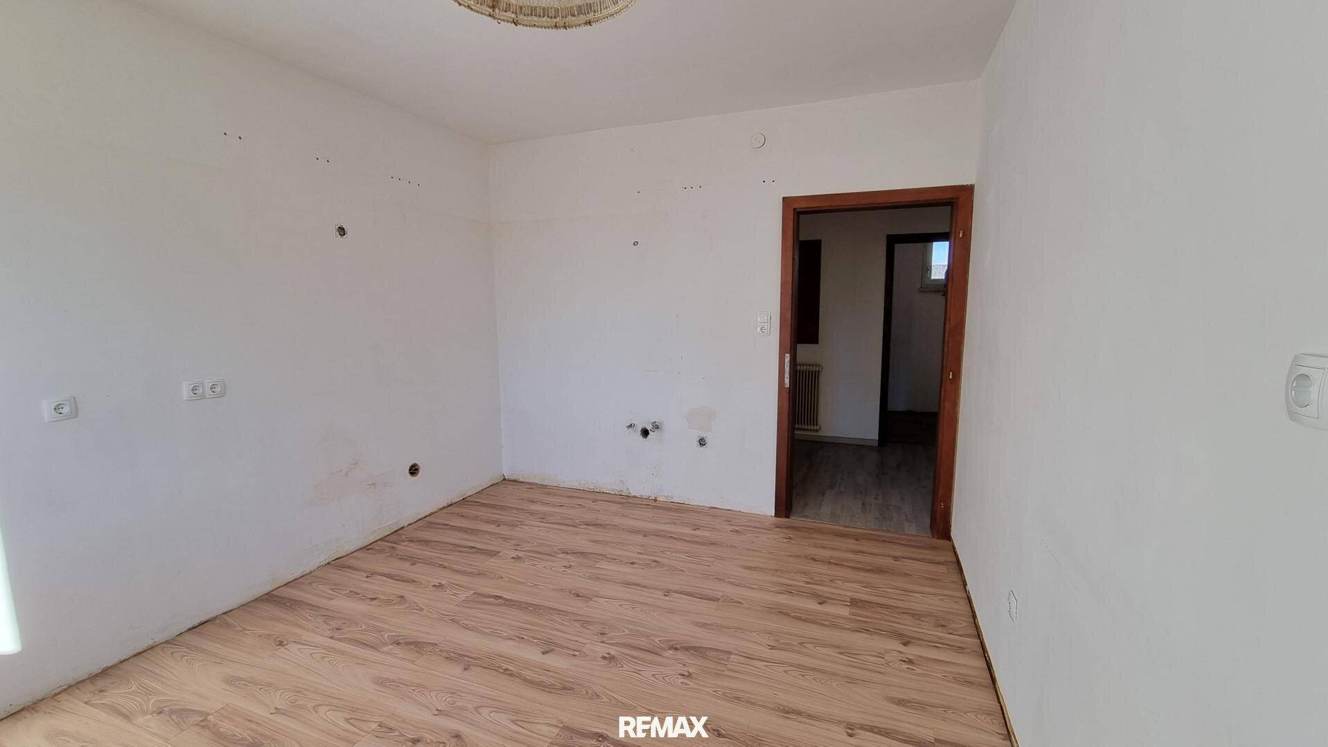 Helles Zimmer mit Laminatboden und Zugang zu einem weiteren Raum, gut gepflegt.