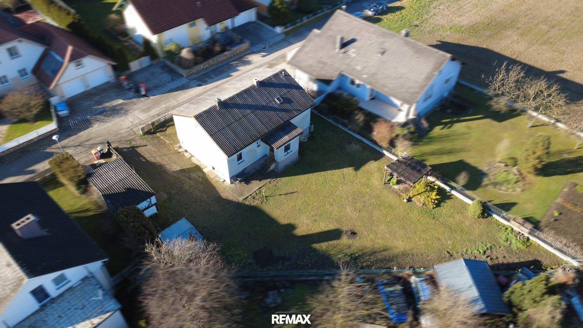 Vogelperspektive des Hauses mit großem Grundstück und umliegenden Gebäuden in sonniger Lage.