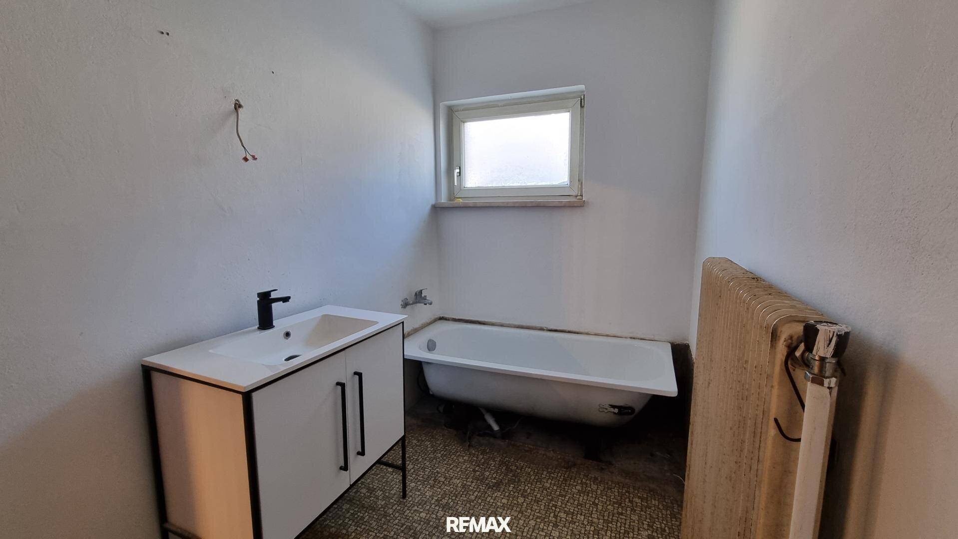 Badezimmer mit neuer Waschtischkonsole, Badewanne und Fenster für Tageslicht.