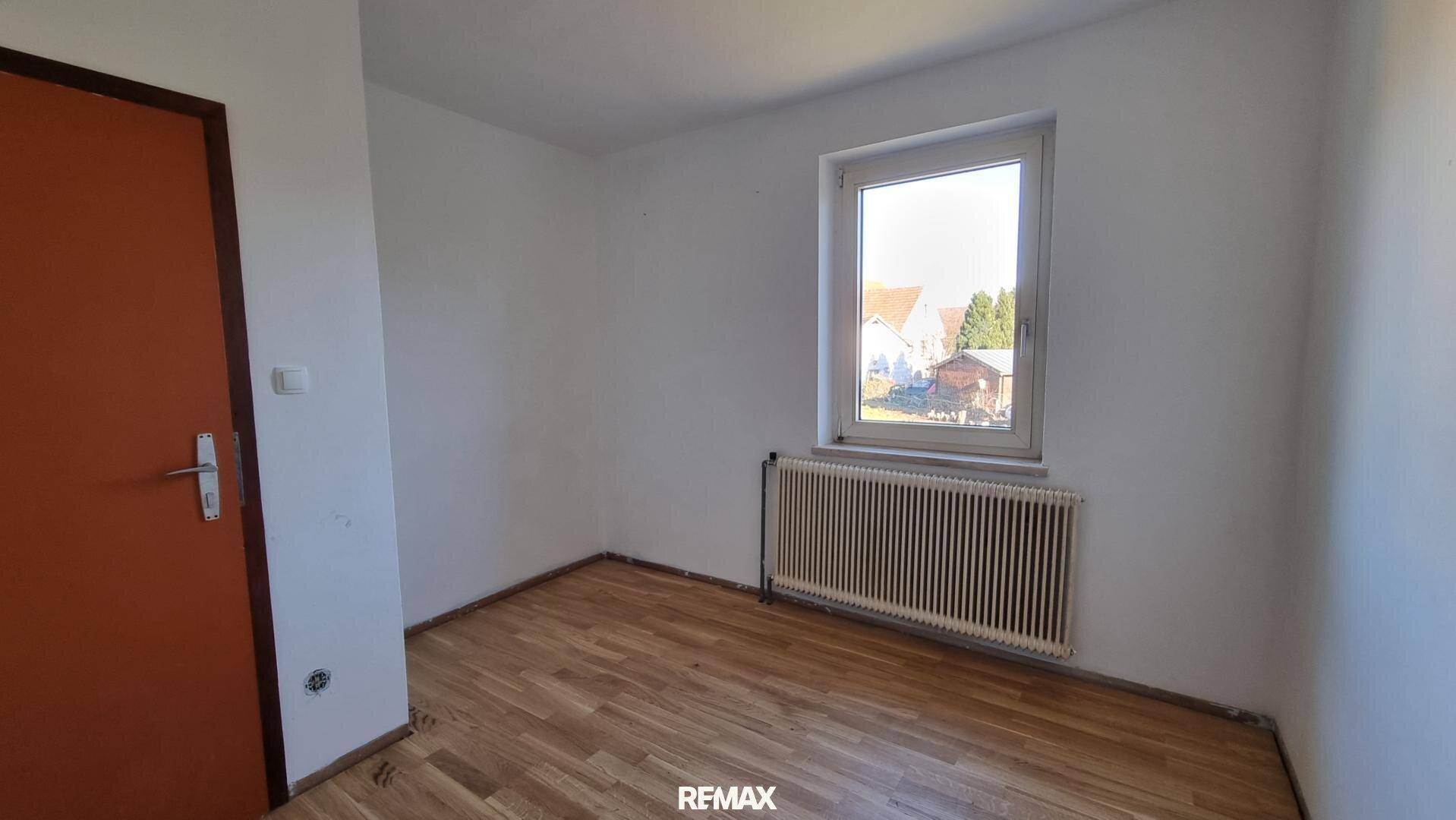 Schlafzimmer mit Laminatboden und Fenster, das eine angenehme Helligkeit bietet.