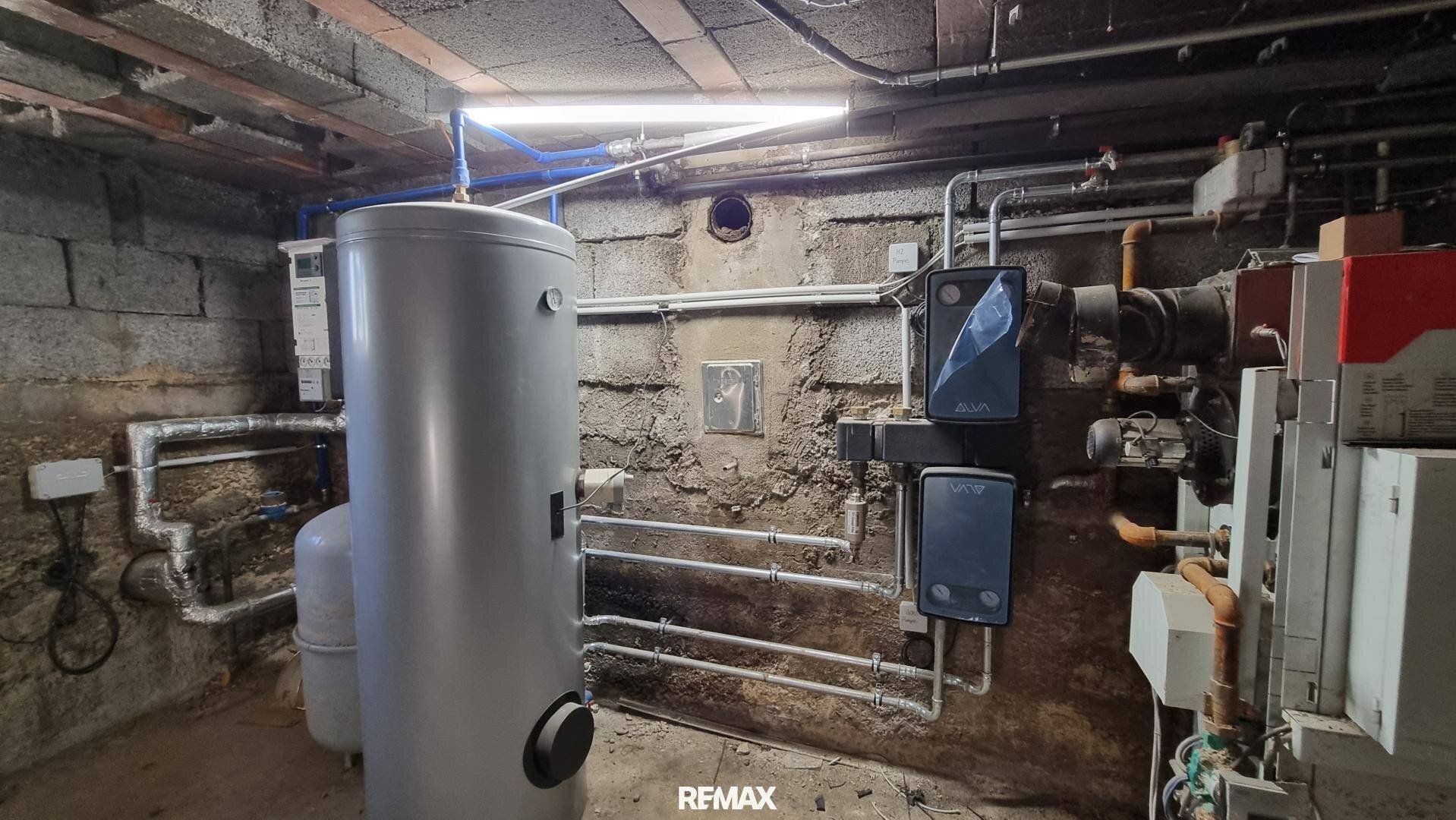 Heizungsraum im Keller mit moderner Heizungsanlage und Warmwasserspeicher.