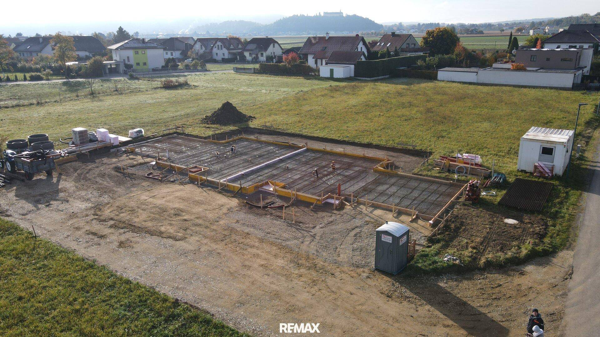 Luftaufnahme einer Baustelle mit frisch gegossener Bodenplatte und ländlicher Umgebung.