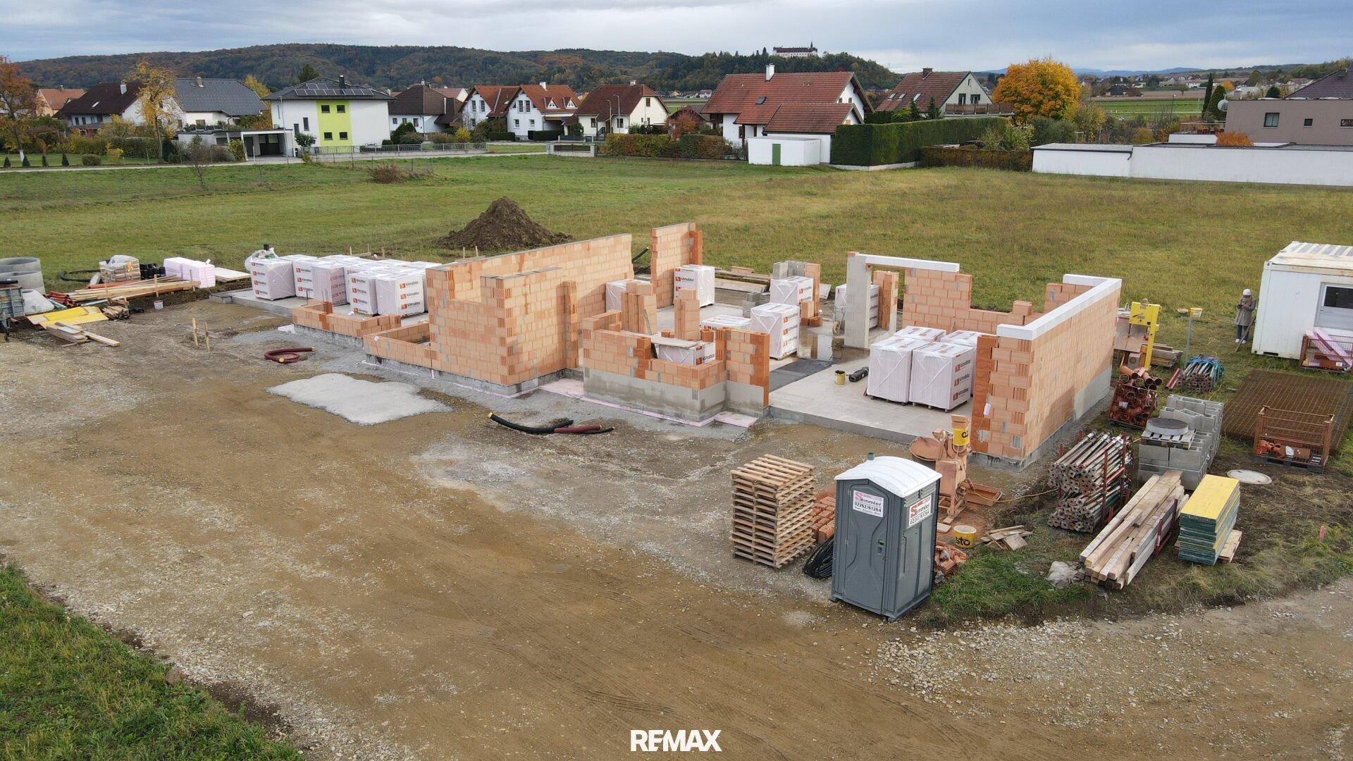 Luftaufnahme einer Baustelle mit fortgeschrittenem Mauerwerk des Erdgeschosses.