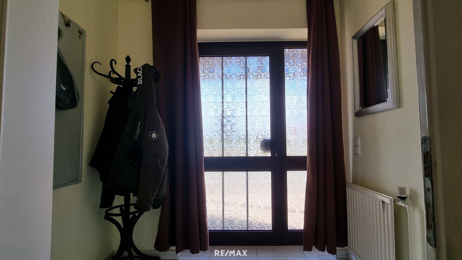 Eingangsbereich mit Garderobe und Fenster, das Tageslicht hereinlässt.