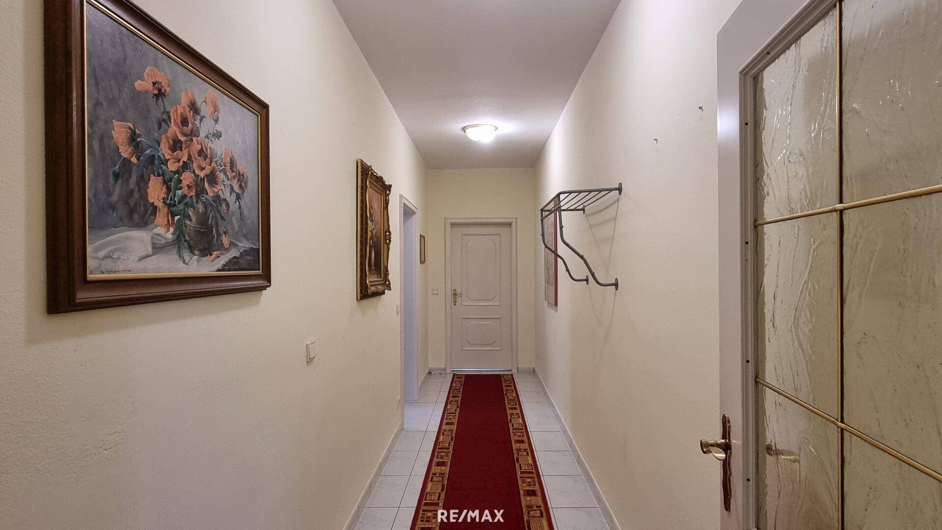 Langer Flur mit Fliesenboden und Teppichläufer, der zu weiteren Räumen führt.