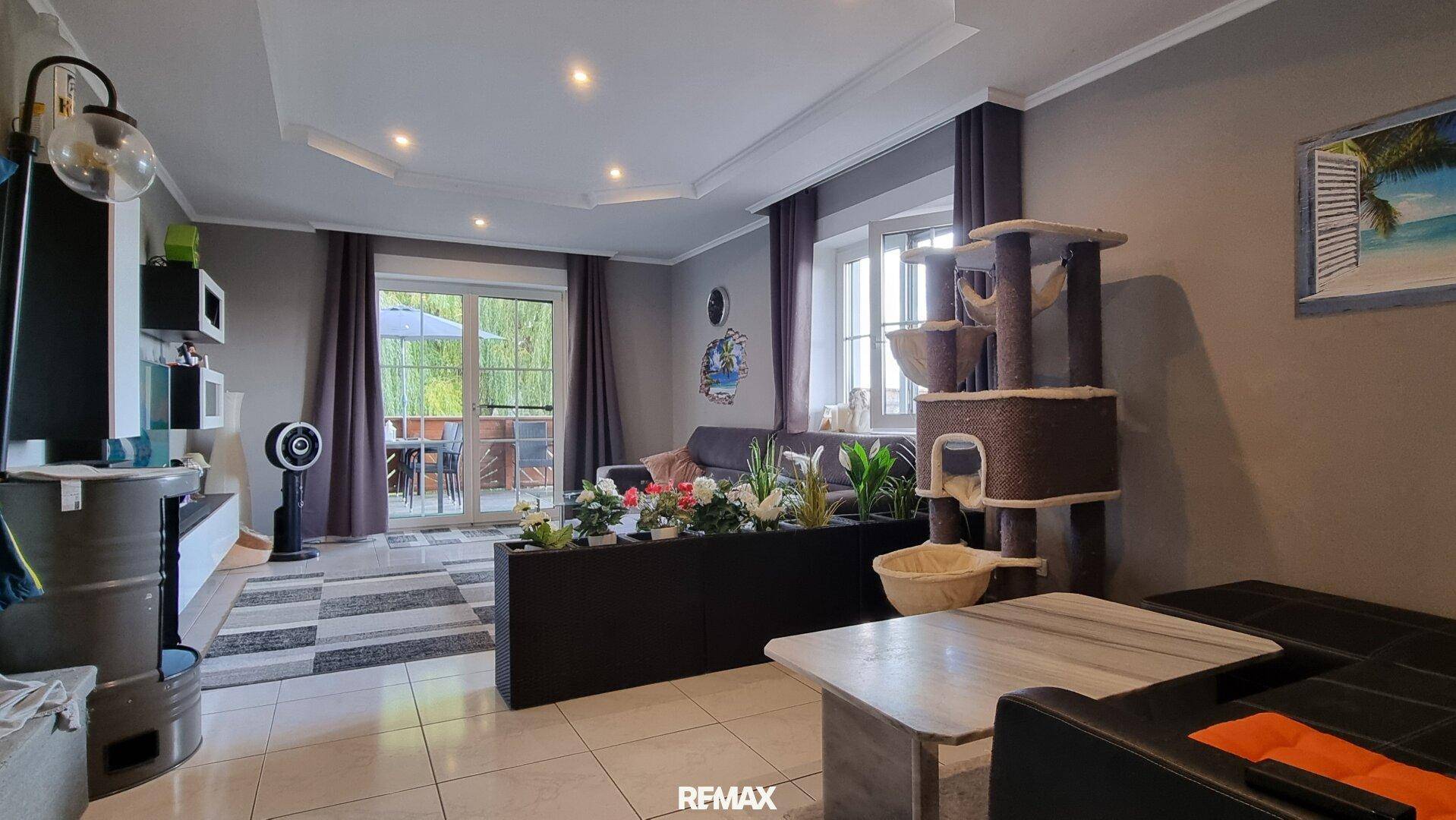 Geräumiges Wohnzimmer mit Pflanzen und Zugang zur Terrasse, modern eingerichtet und hell.