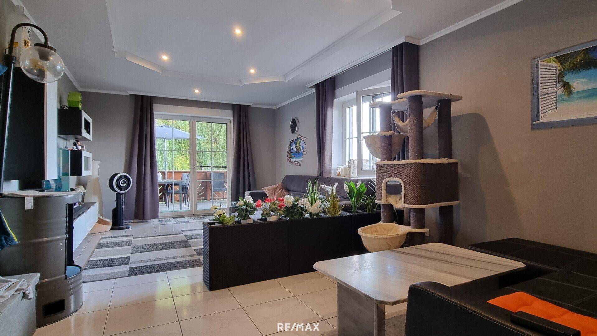 Geräumiges Wohnzimmer mit Sofa, Fliesenboden und dekorativem Raumteiler.