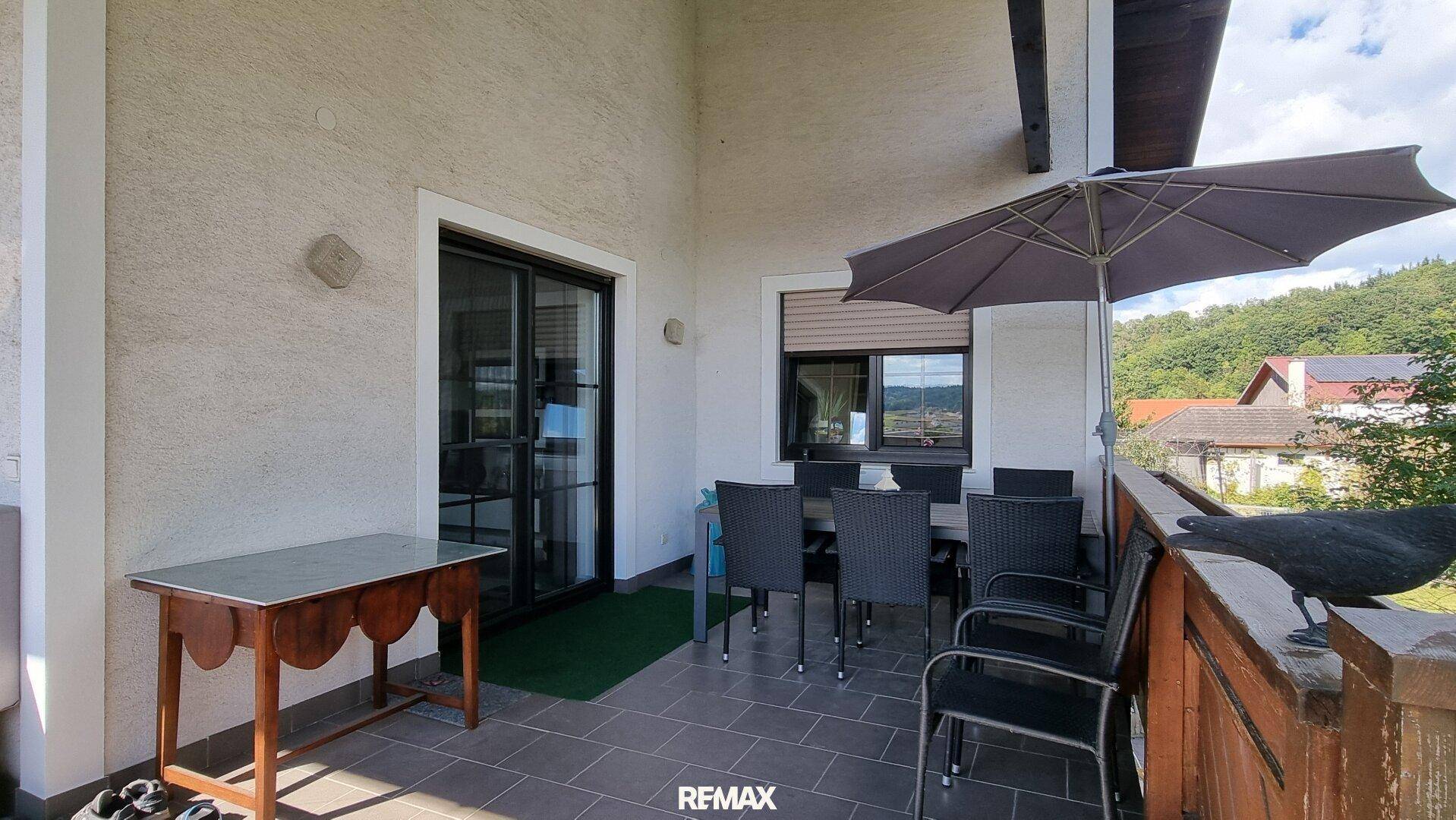 Überdachter Balkon mit Esstisch und Stühlen, ideal für Mahlzeiten im Freien mit Aussicht.