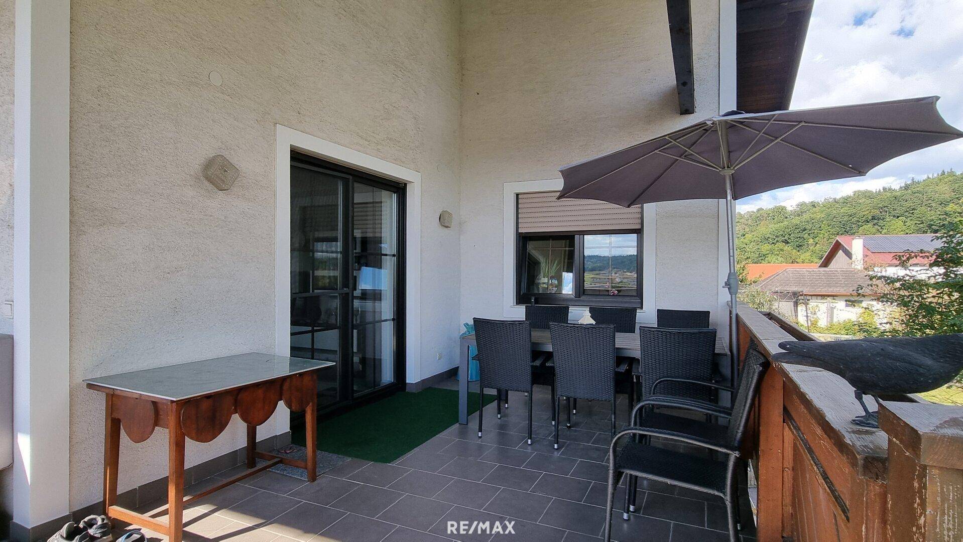 Überdachte Terrasse mit Esstisch und Stühlen, ideal für Mahlzeiten im Freien.