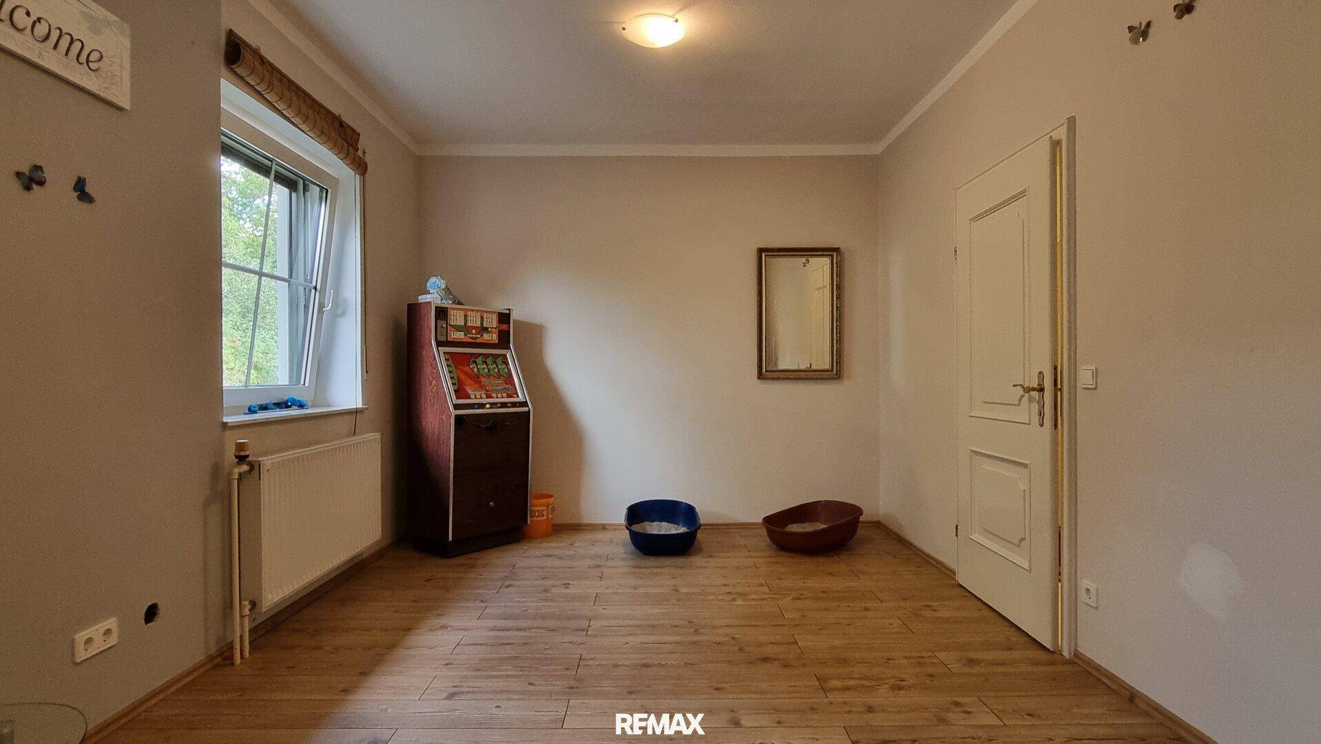 Geräumiges Zimmer mit Holzboden und Fenster, derzeit als Spielzimmer genutzt.