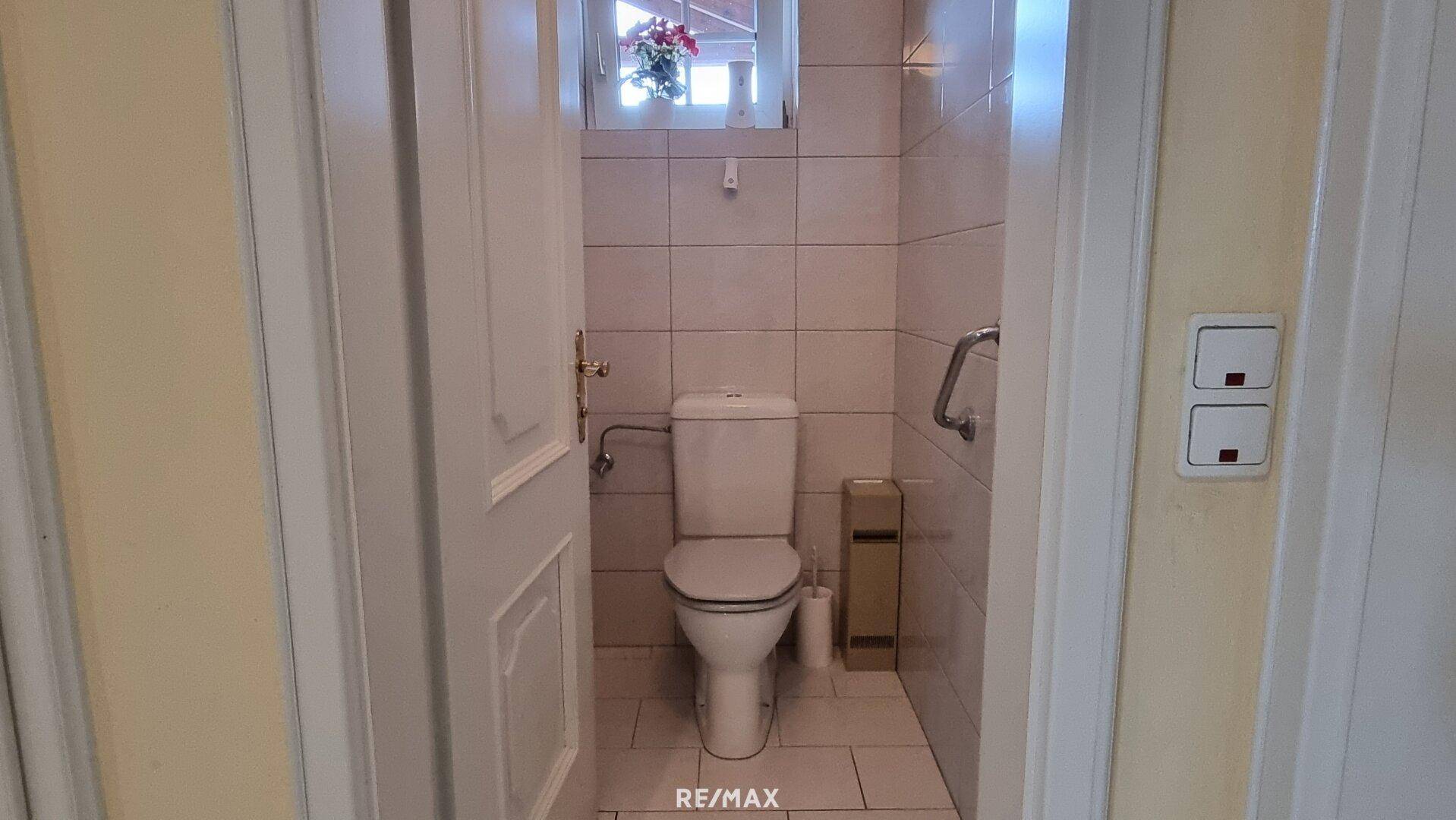 Separates Gäste-WC mit Toilette und Haltegriffen für zusätzliche Sicherheit.