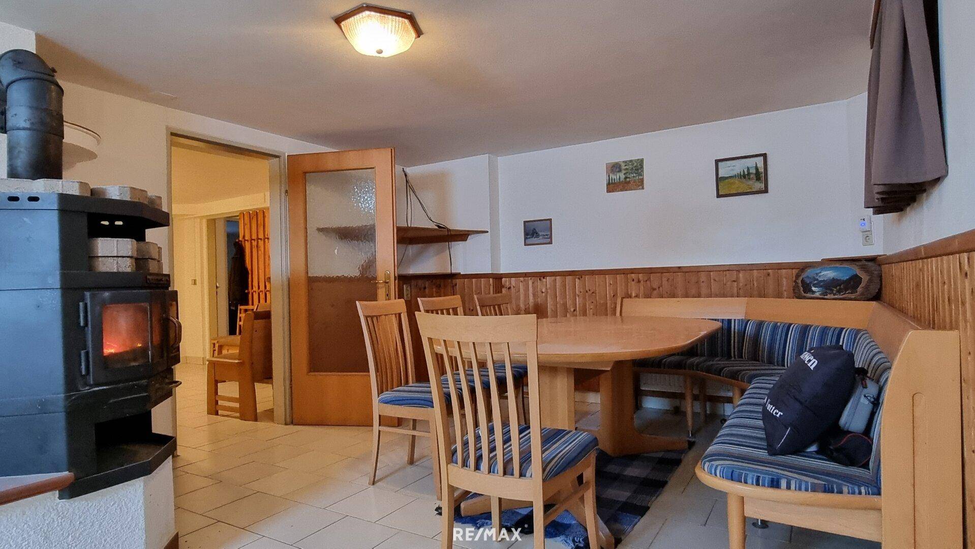 Essbereich im Keller mit Holztisch, Eckbank und einem Holzofen für gemütliche Wärme.