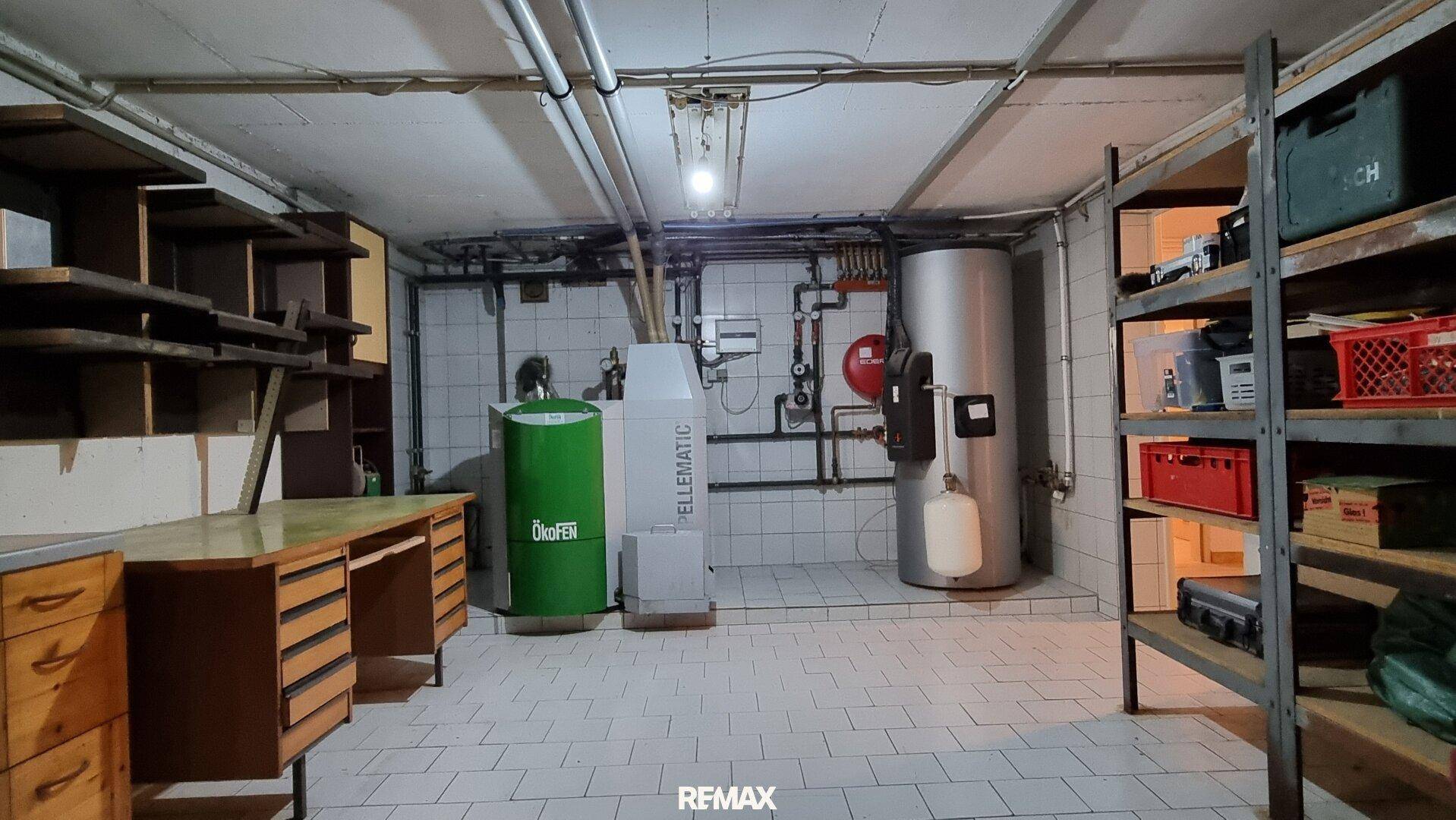 Heizungsraum im Keller mit Heizkessel und Regalen, dient als Technik- und Lagerraum.