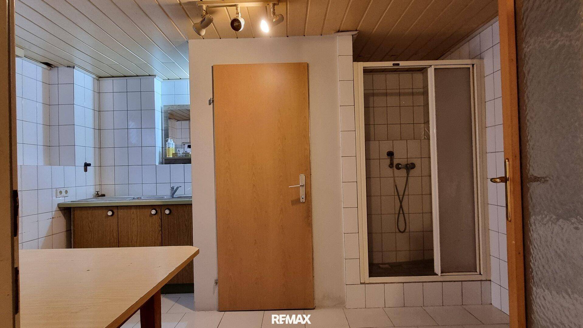 Einfaches Badezimmer im Keller mit Dusche und Fliesen, funktional und praktisch.