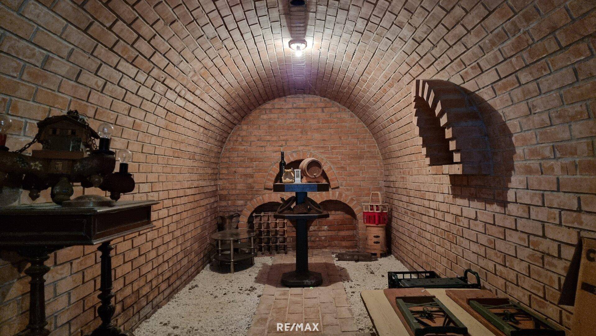 Gewölbter Weinkeller mit Ziegelwänden, Weinregalen und rustikaler Dekoration.