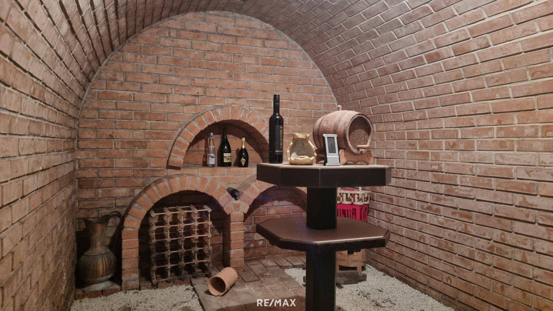 Detailansicht des Weinkellers mit Ziegelgewölbe, Weinregalen und Flaschen.