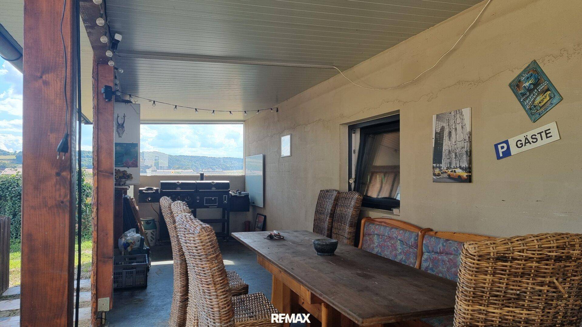 Überdachte Terrasse mit Korbmöbeln und Esstisch, ideal für Mahlzeiten im Freien mit Weitblick.