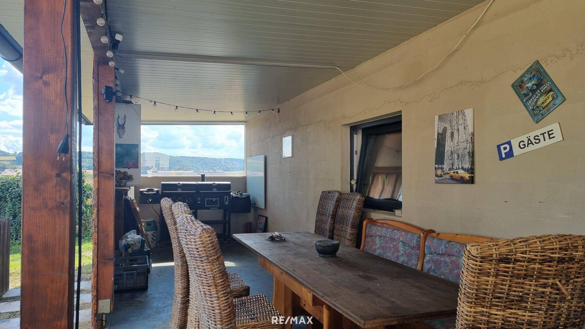 Überdachter Außenbereich mit großem Esstisch und Stühlen, ideal für gesellige Runden.