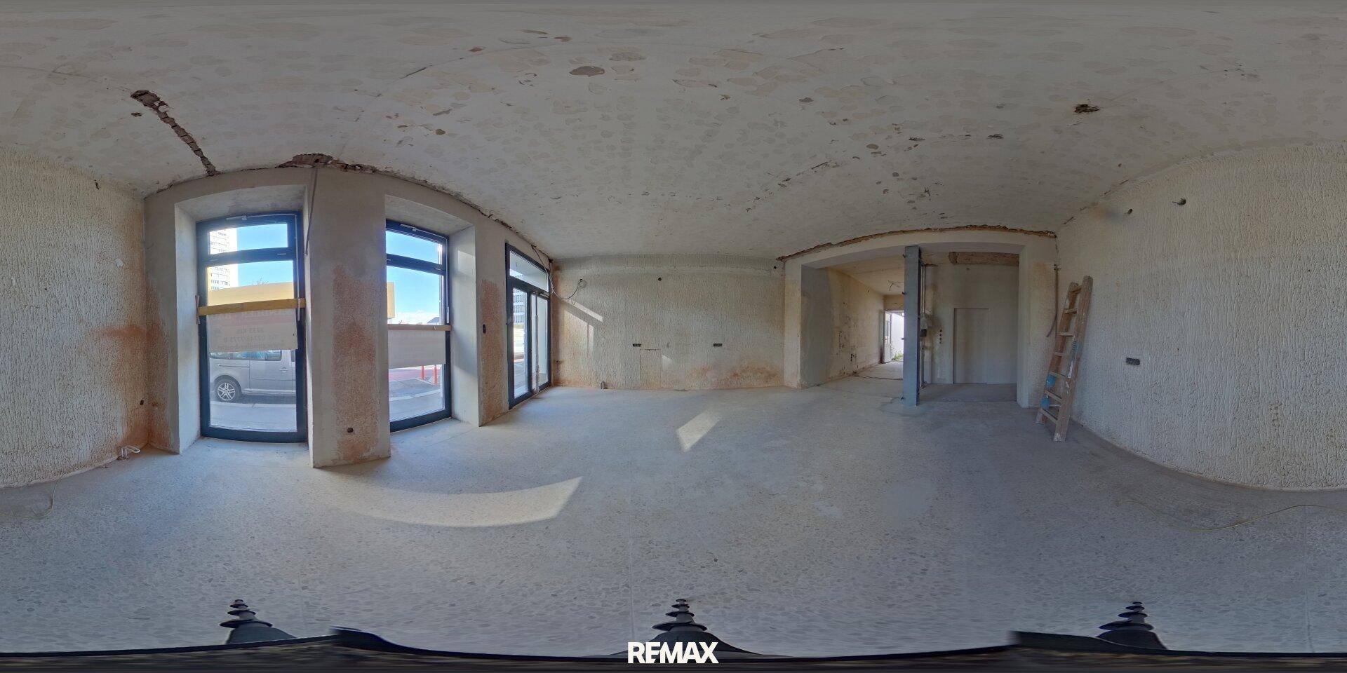 Panoramaansicht eines großen Geschäftsraums im Rohbau mit Blick auf die Straße durch Fenster.