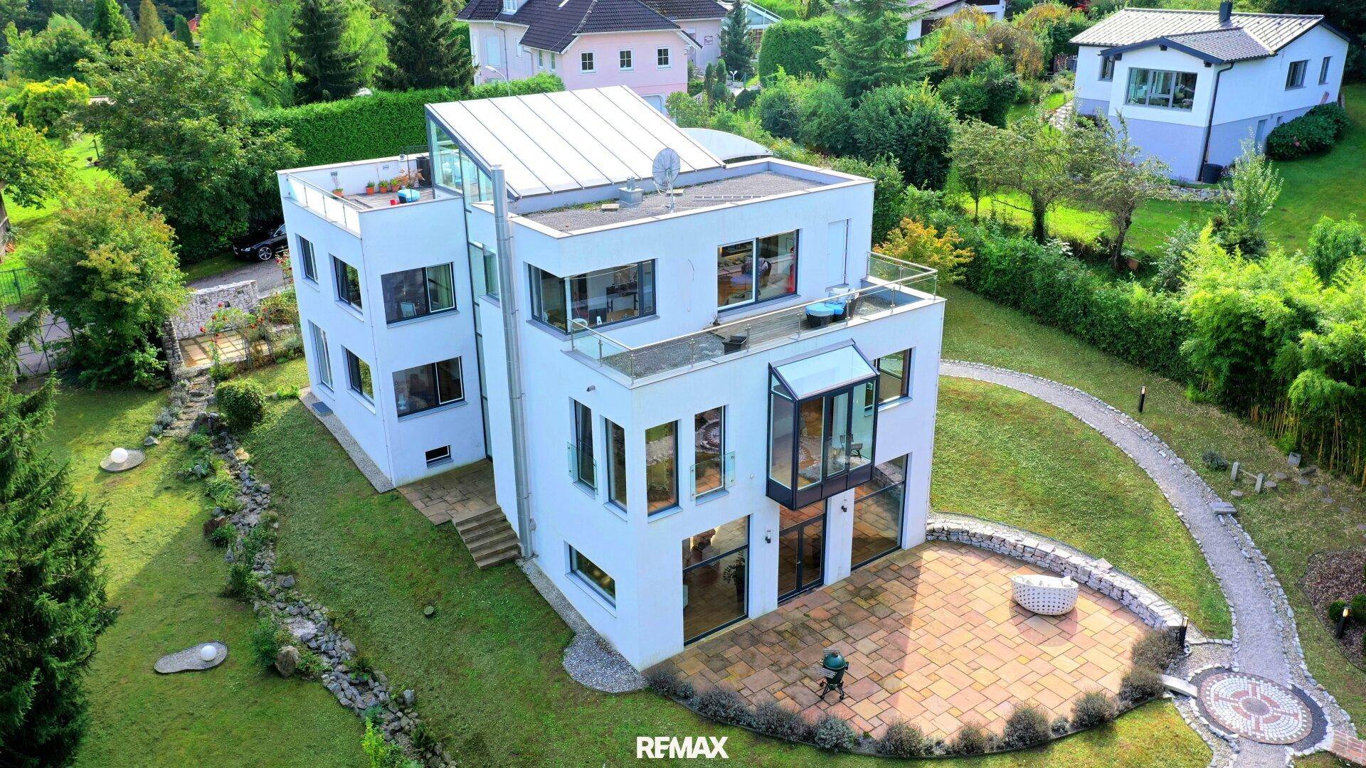 Luftaufnahme der modernen Villa mit Flachdach, großzügiger Terrasse und weitläufigem Grundstück.
