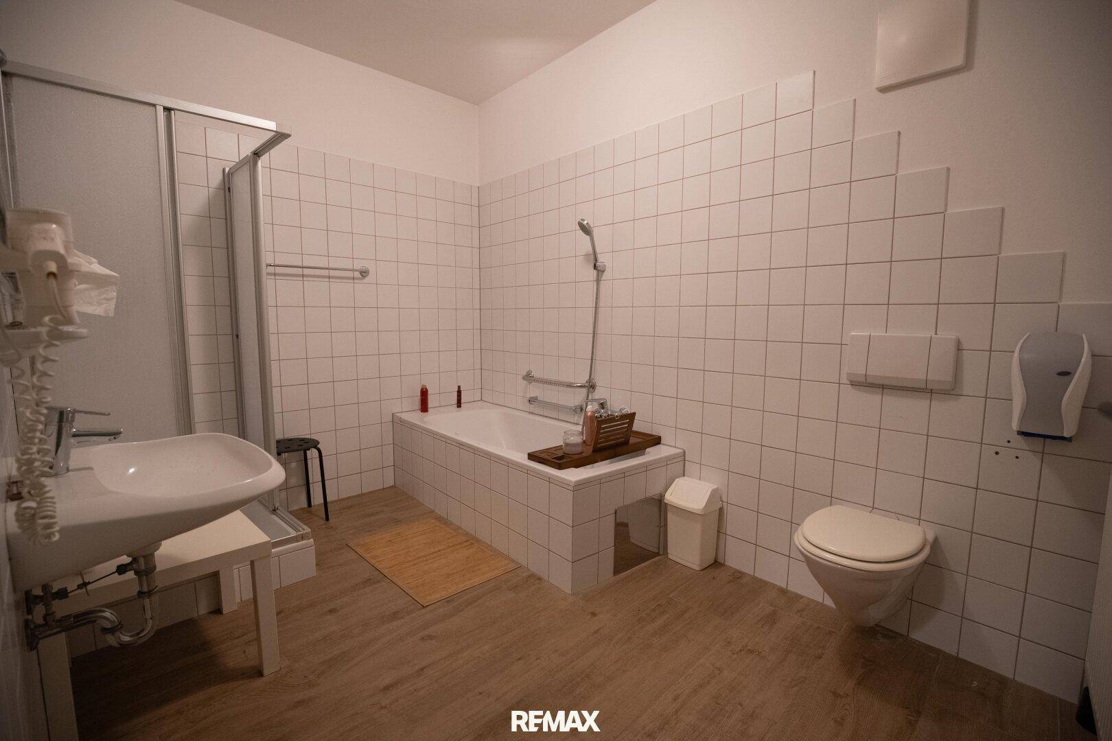 Geräumiges Badezimmer mit Badewanne, Duschbereich, WC und Waschbecken.