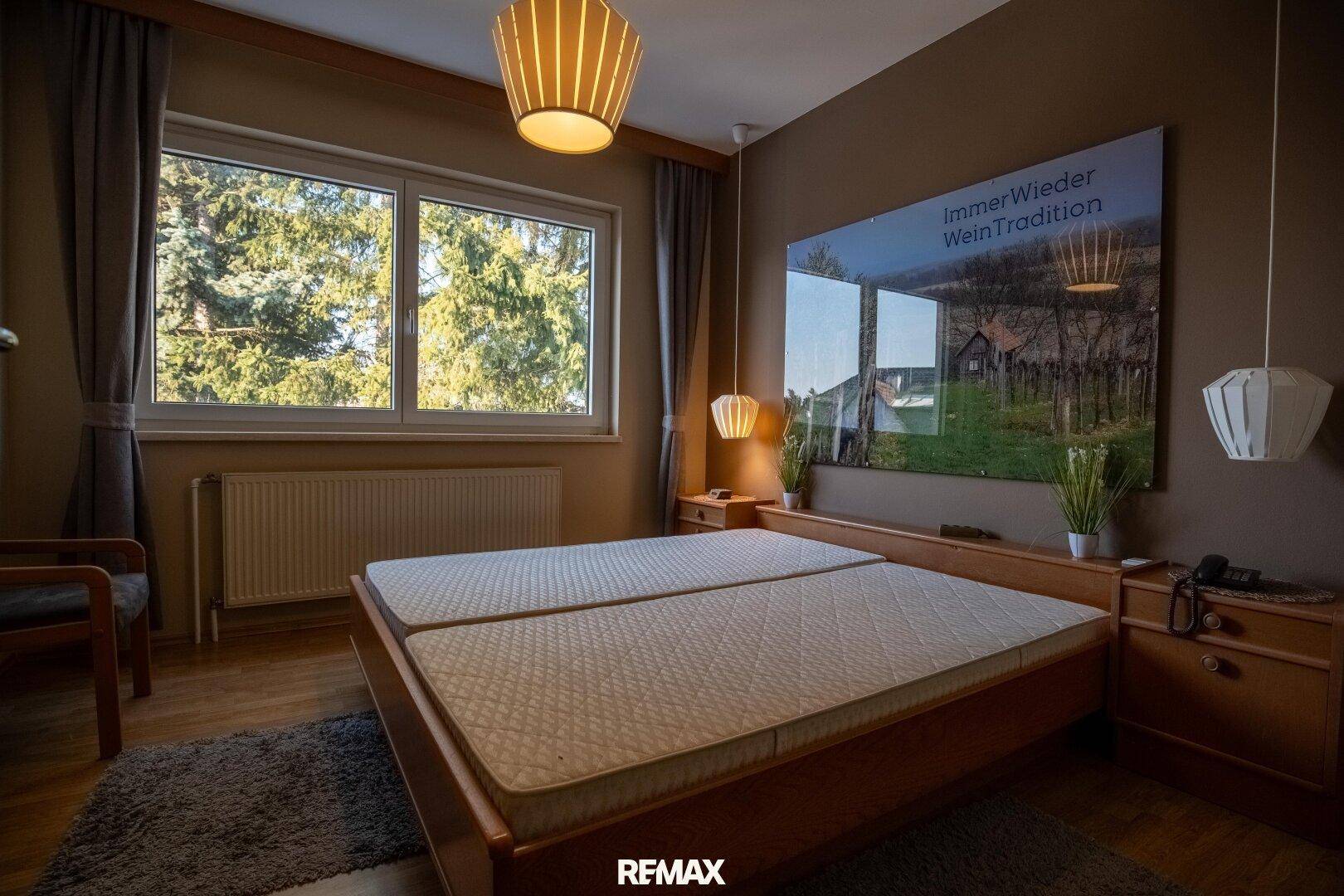 Gemütliches Schlafzimmer mit Doppelbett, Holzboden und Blick ins Grüne.