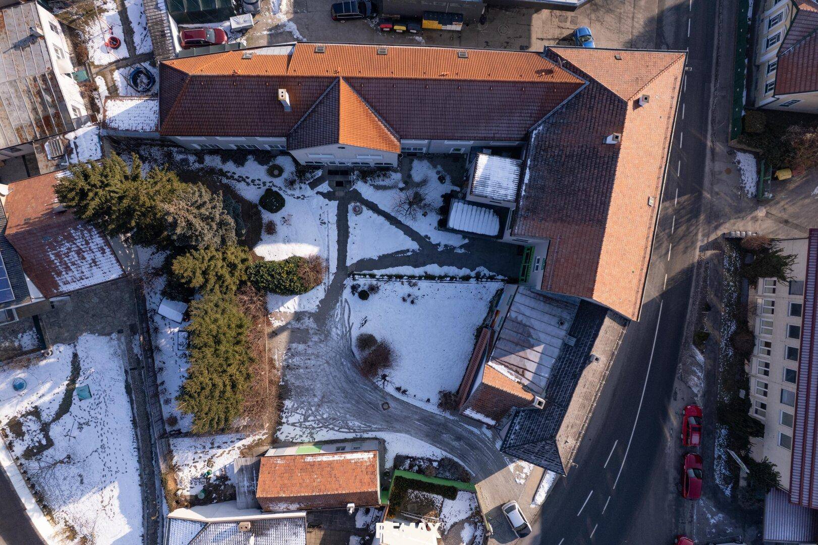 Luftaufnahme des Anwesens mit Gebäuden, Gartenflächen und umliegender Bebauung.