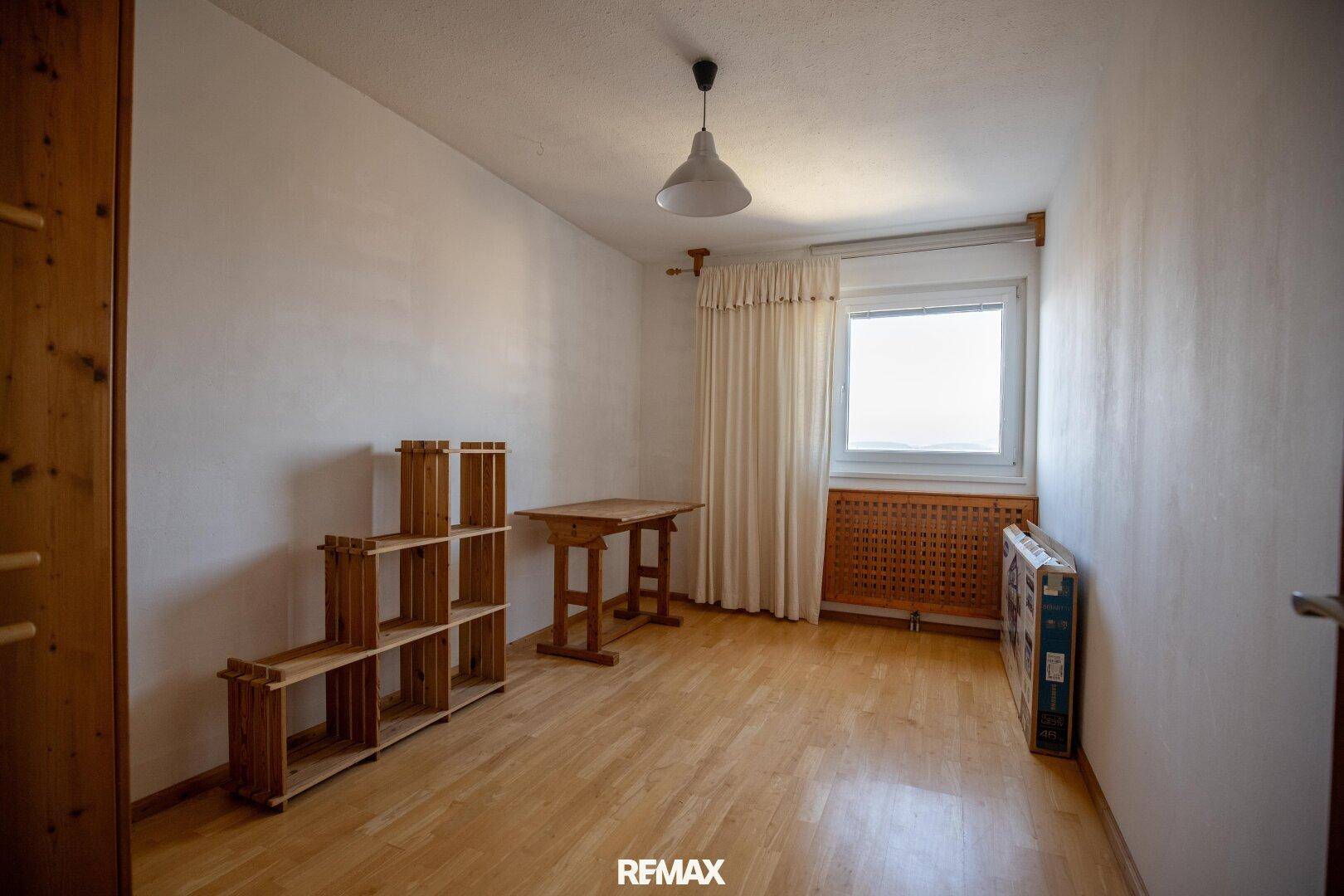 Leeres Zimmer mit hellem Holzboden, Fenster und einfacher Einrichtung, ideal als Schlaf- oder Arbeitszimmer.