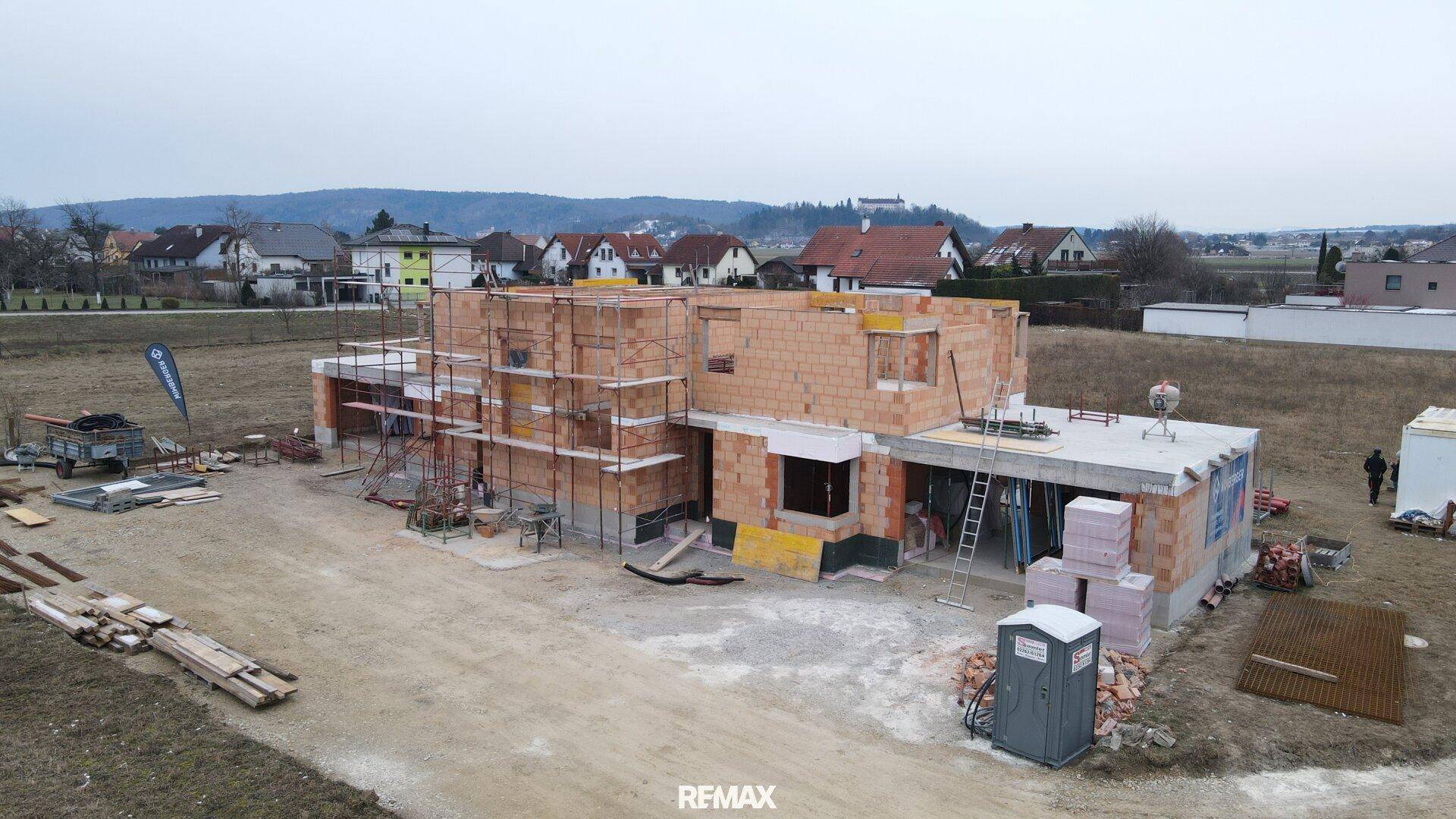 Luftaufnahme einer Baustelle mit Rohbau und Gerüst für weitere Bauarbeiten.