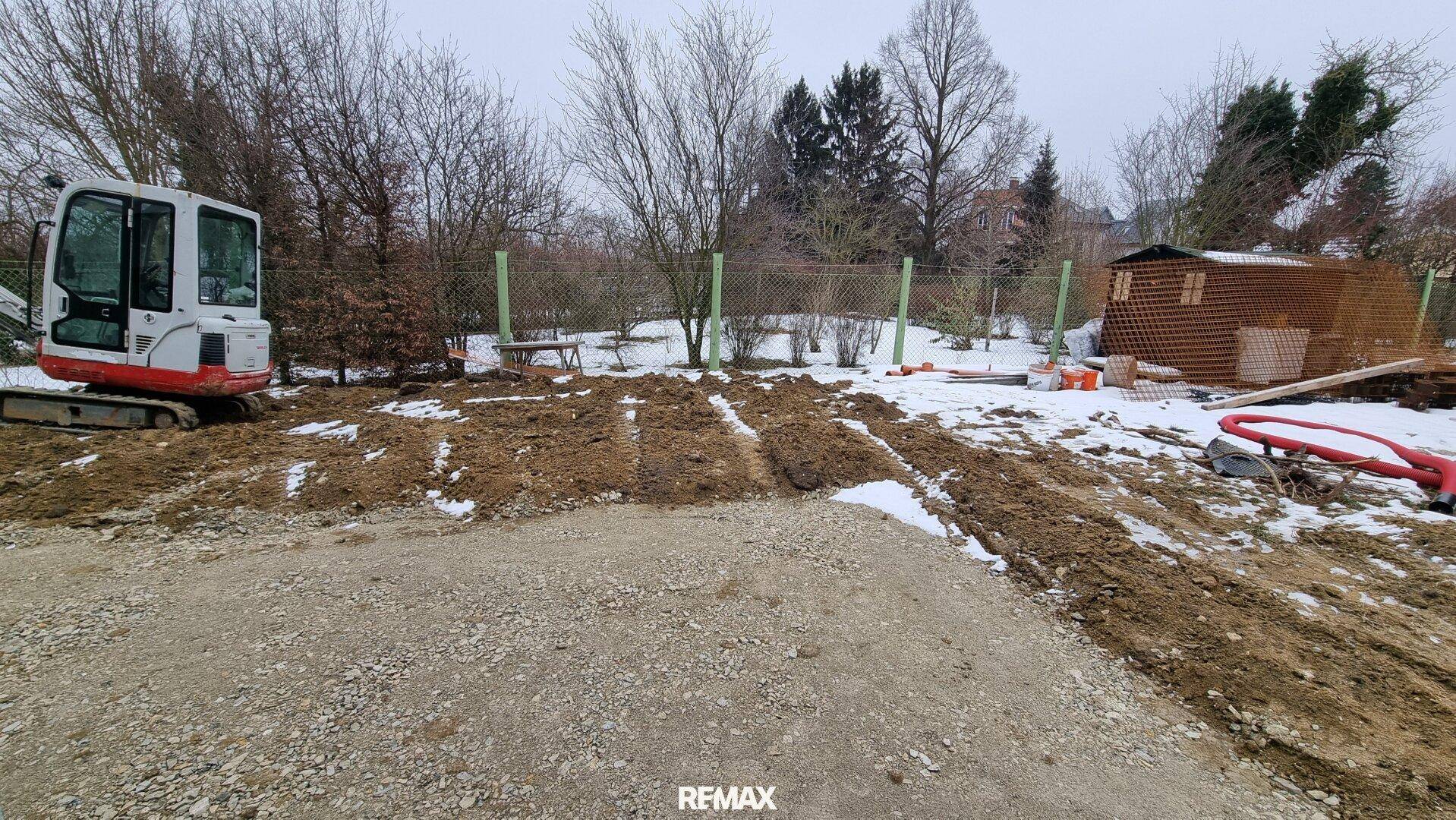 Großer, unfertiger Gartenbereich mit Bagger und Blick auf die Umgebung.