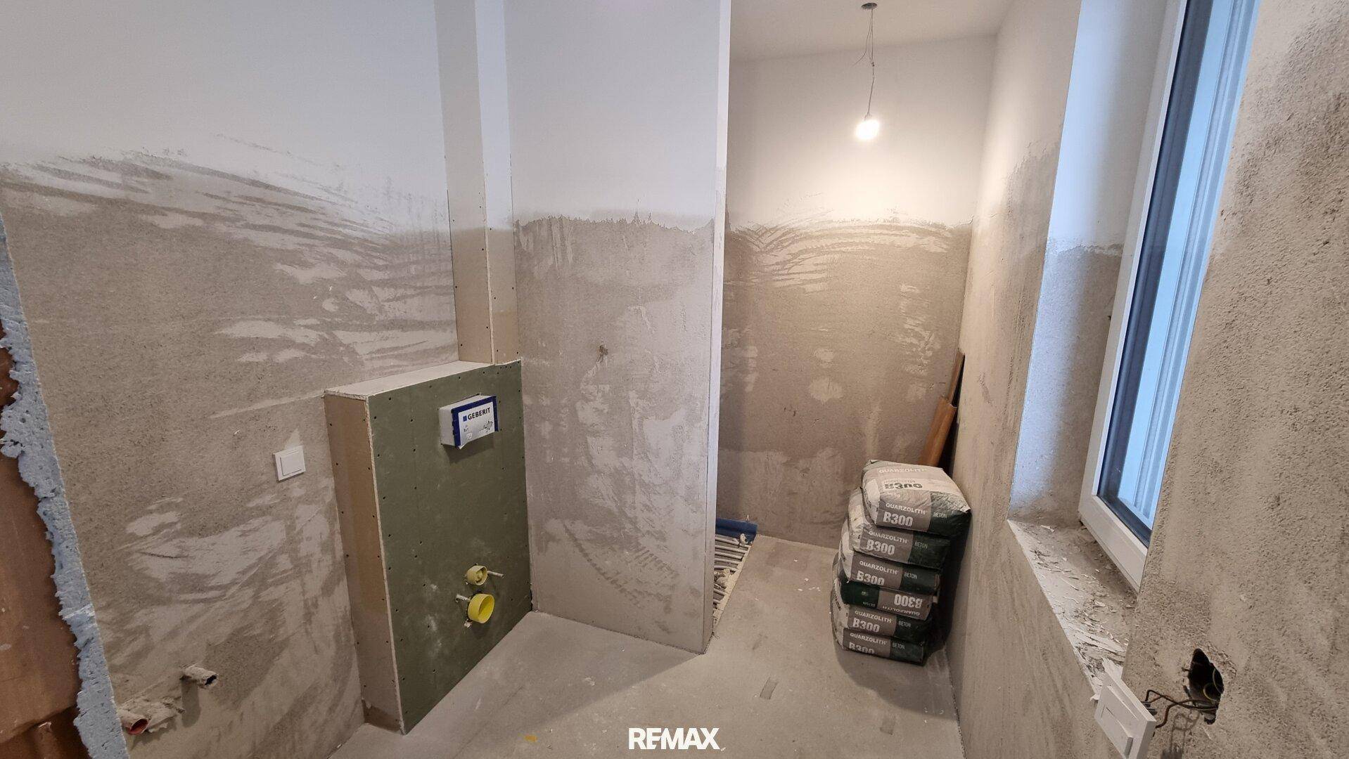 Unfertiges Badezimmer oder Gäste-WC mit vorbereiteten Installationen und kleinem Fenster.