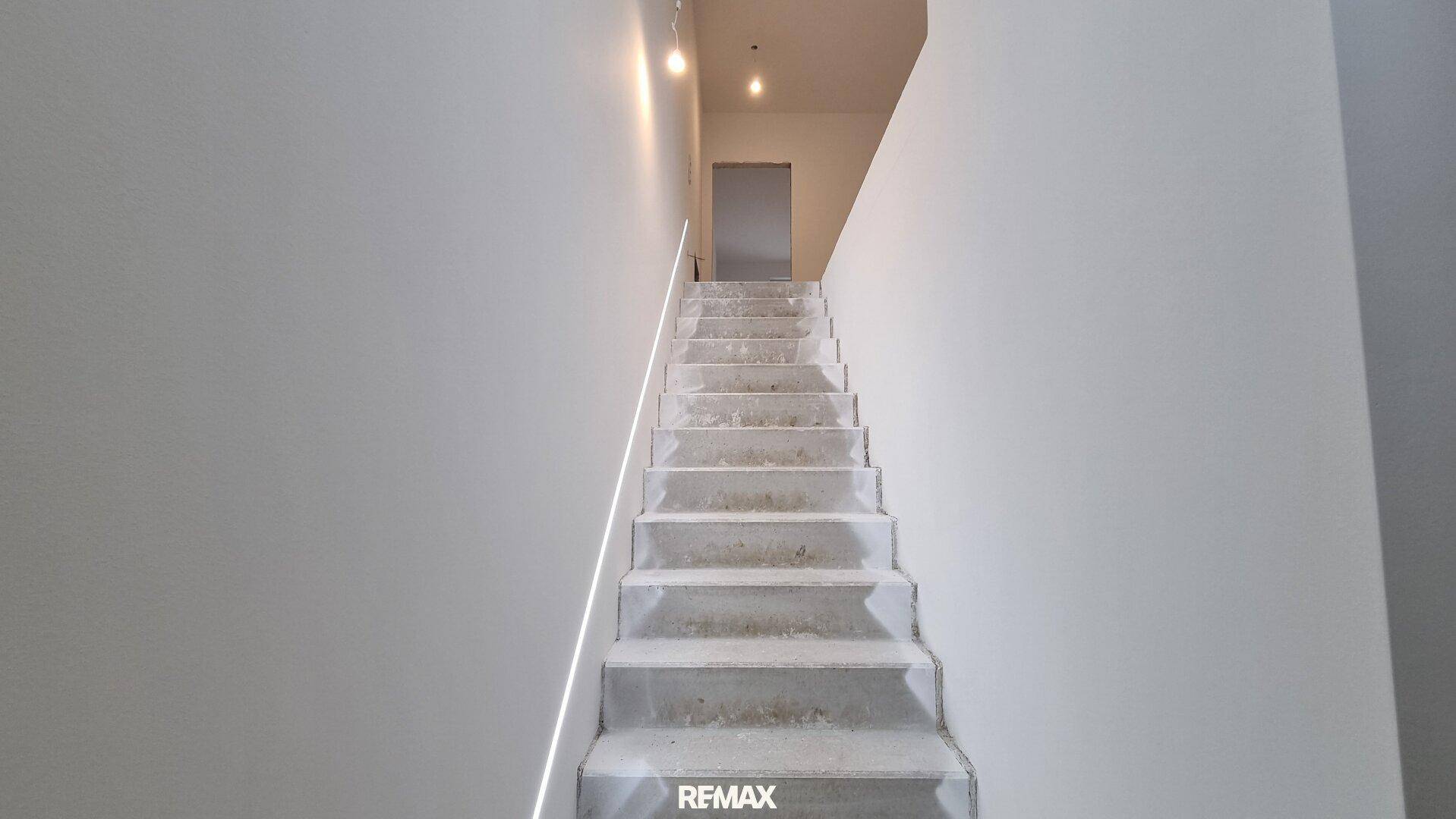Unfertiges Treppenhaus mit Betonstufen und schlichten weißen Wänden im Neubau.