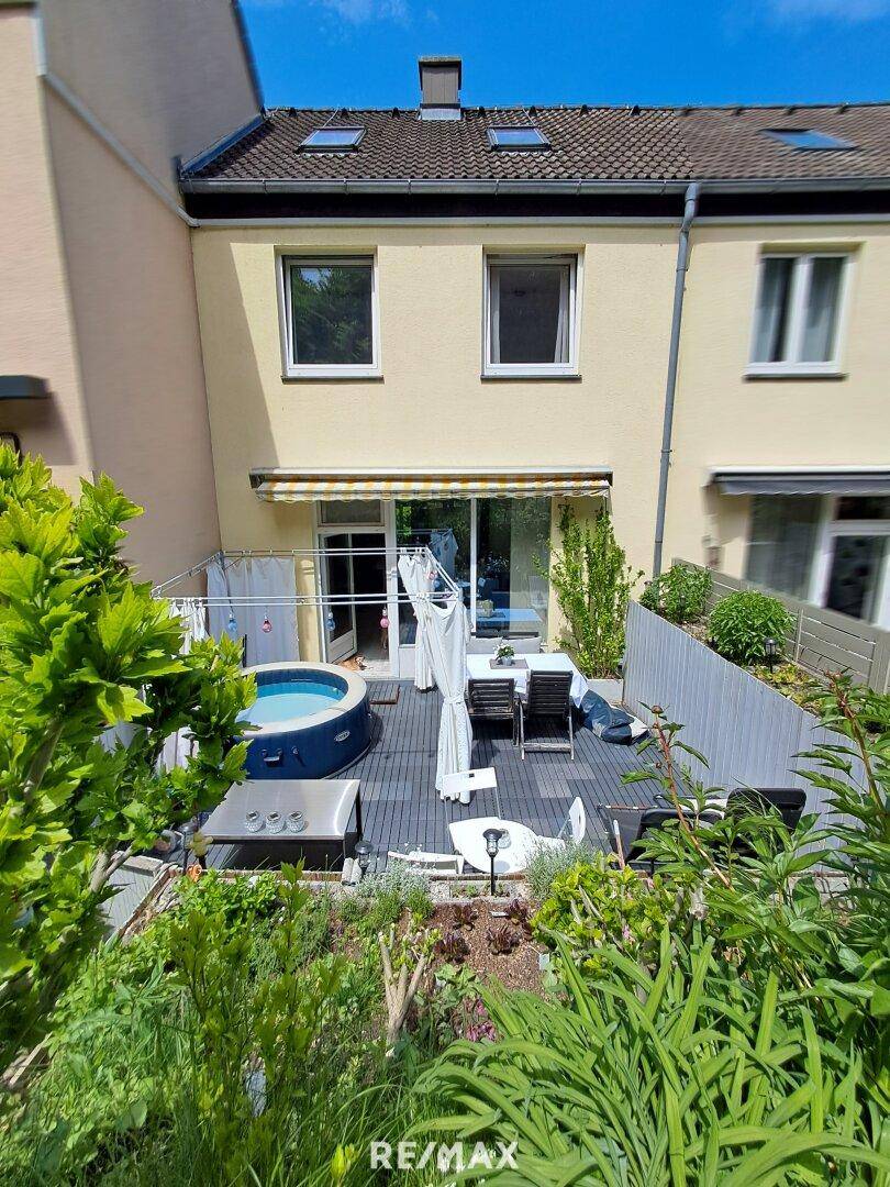 Rückansicht des Hauses mit großer Terrasse, Whirlpool und Gartenbereich.
