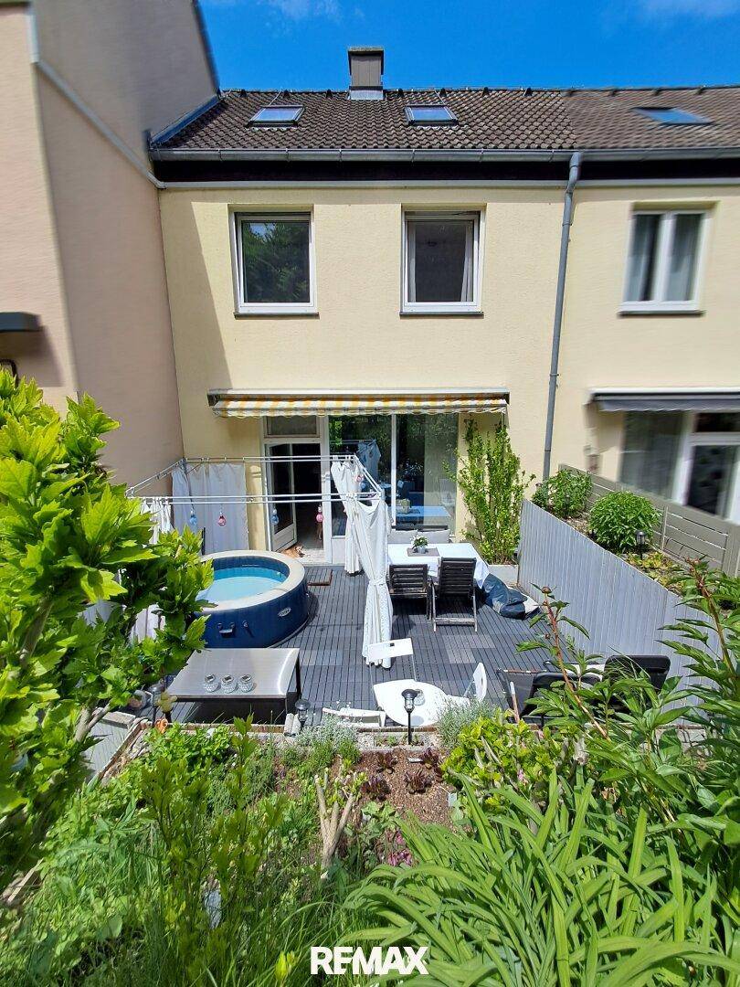 Rückansicht des Hauses mit großer Terrasse, Whirlpool und Gartenbereich am Hang.