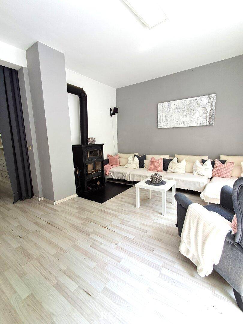 Gemütliches Wohnzimmer mit Holzboden, Kaminofen und moderner Dekoration.