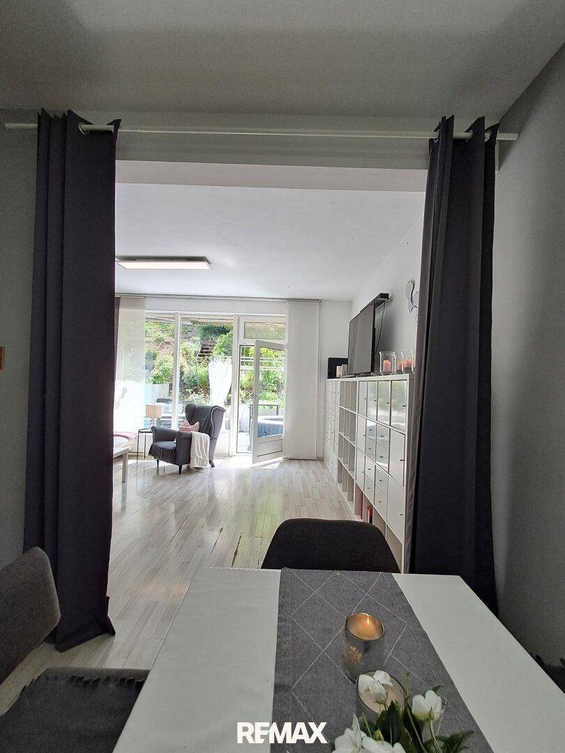Essbereich mit Blick in das helle Wohnzimmer und Zugang zur Außenterrasse.