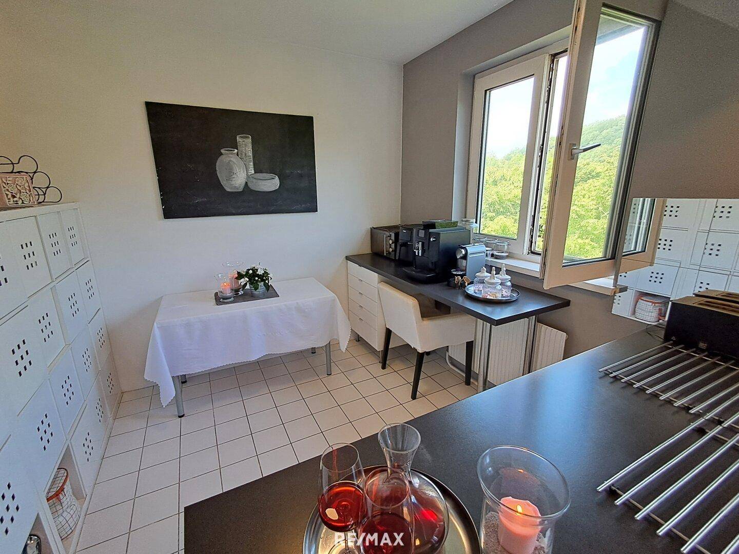 Helle Küche mit Essbereich, weißen Schränken und Blick ins Grüne.