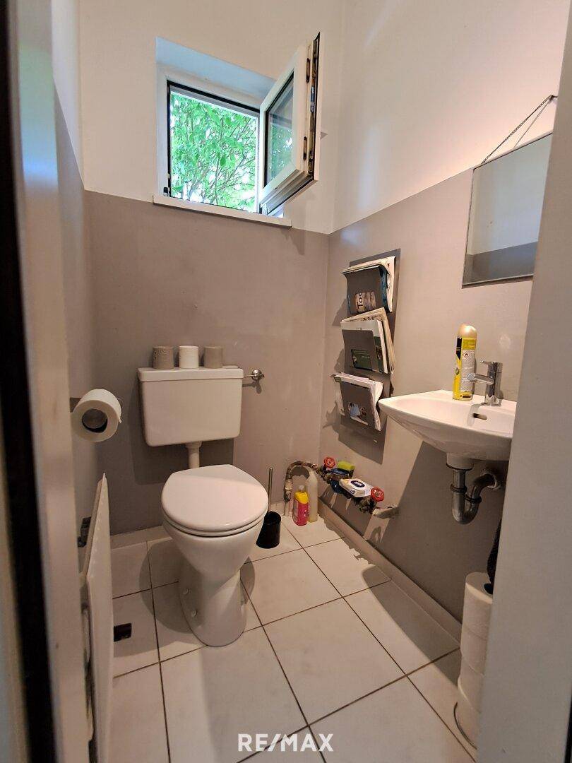 Gäste-WC mit Fenster, Toilette und kleinem Waschbecken.