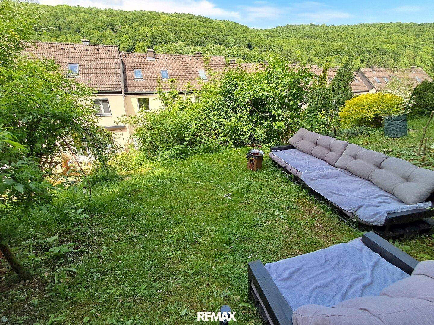 Großer Gartenbereich mit Rasenfläche und Outdoor-Sitzgelegenheiten, umgeben von viel Grün.