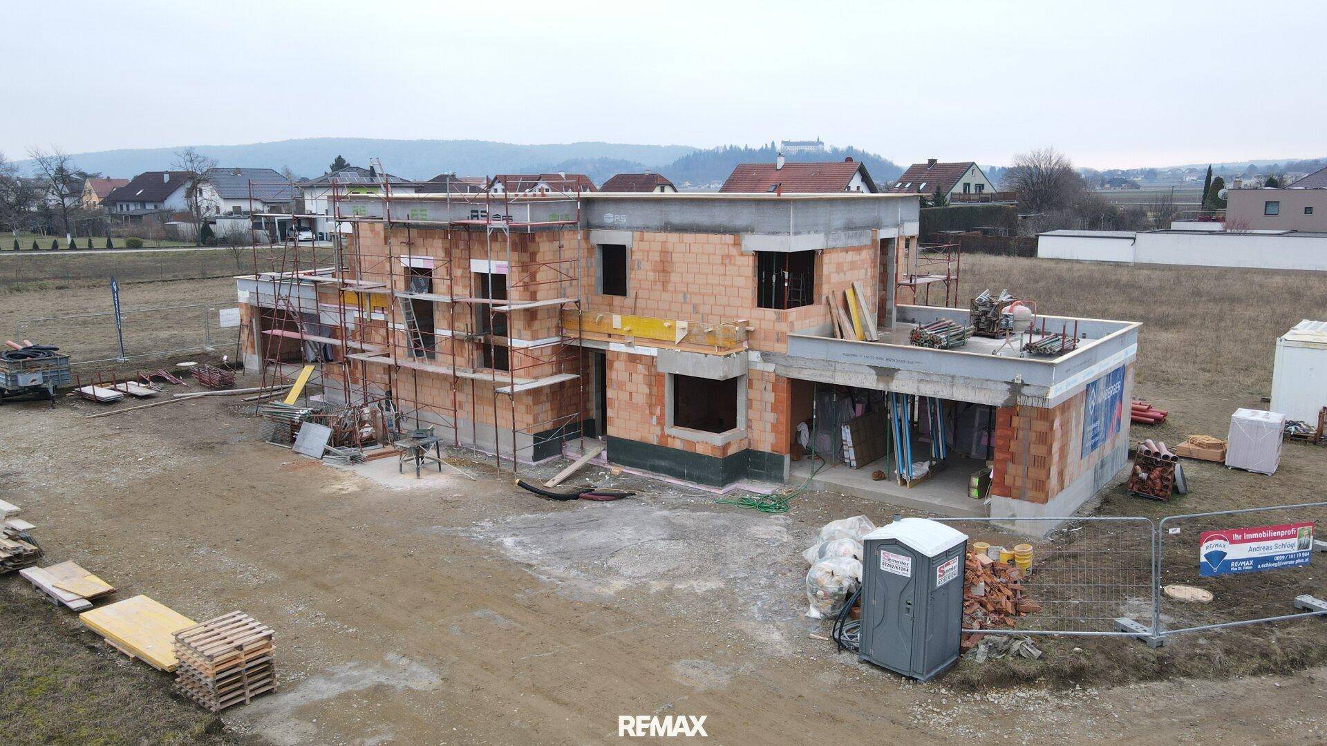 Luftaufnahme einer Baustelle mit Rohbau und Gerüst, bereit für die nächste Bauphase.