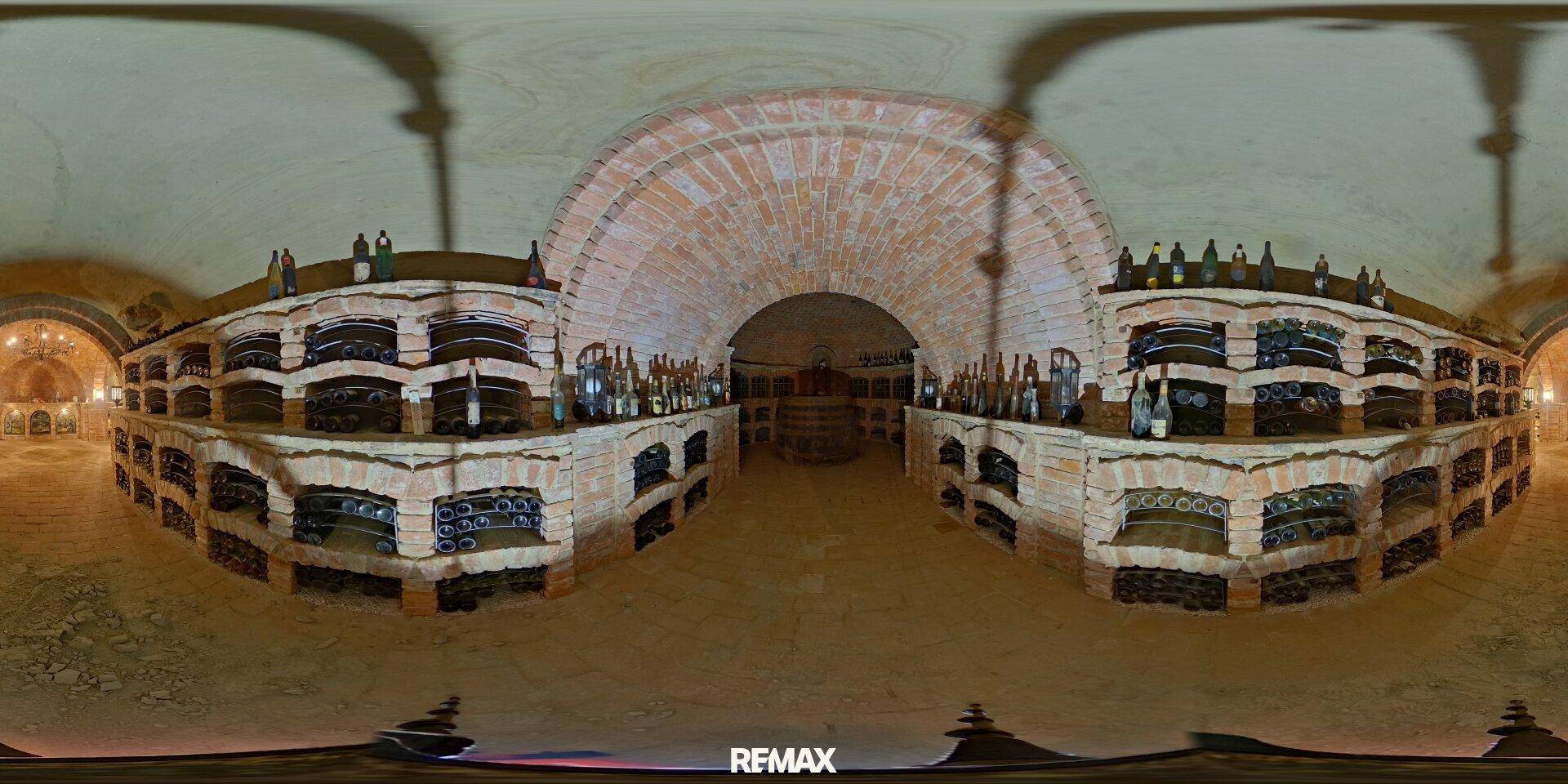 Panoramabild eines Weinkellers mit Ziegelgewölben und beidseitigen Regalen voller Weinflaschen.