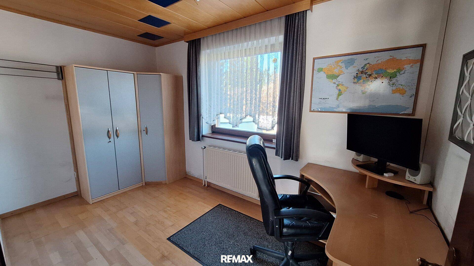Helles Arbeitszimmer mit Laminatboden, großem Fenster und Holzdecke.
