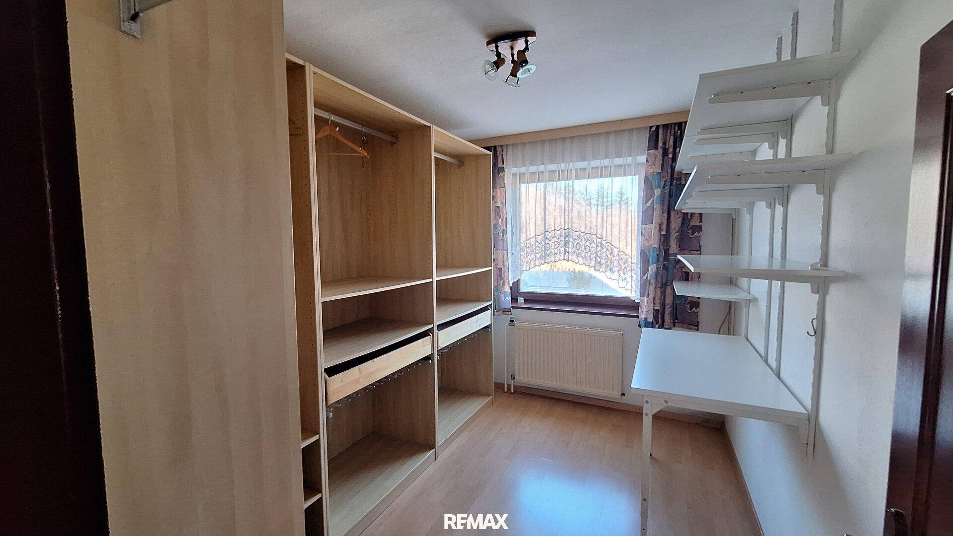 Ankleidezimmer mit offenen Regalen, Kleiderschränken und Laminatboden.