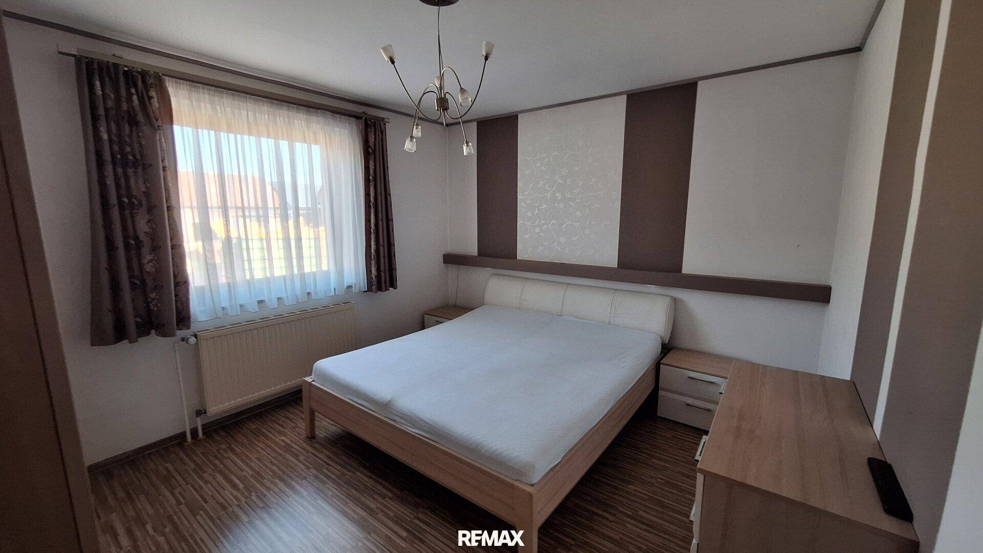 Schlafzimmer mit Doppelbett, Laminatboden und dekorativer Wandgestaltung.