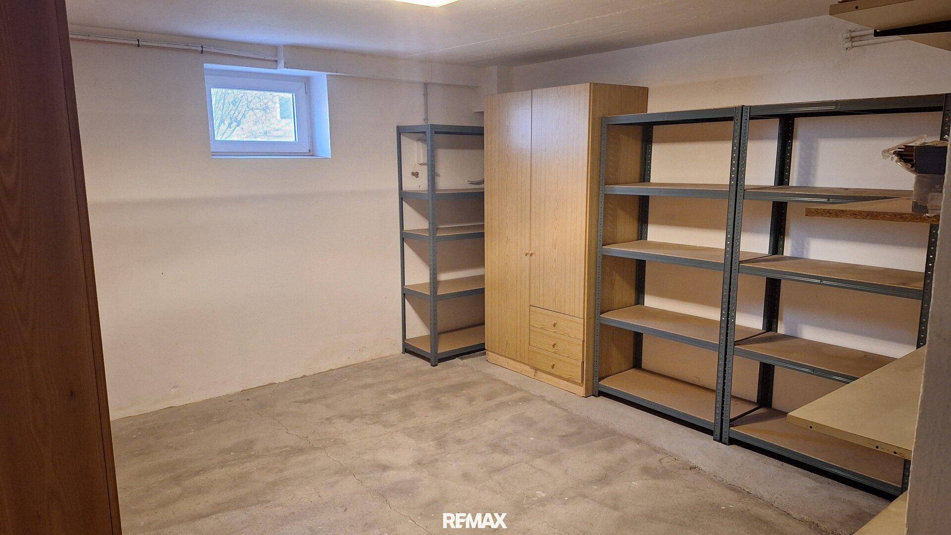 Geräumiger Kellerraum mit Regalen, Schrank und kleinem Fenster.