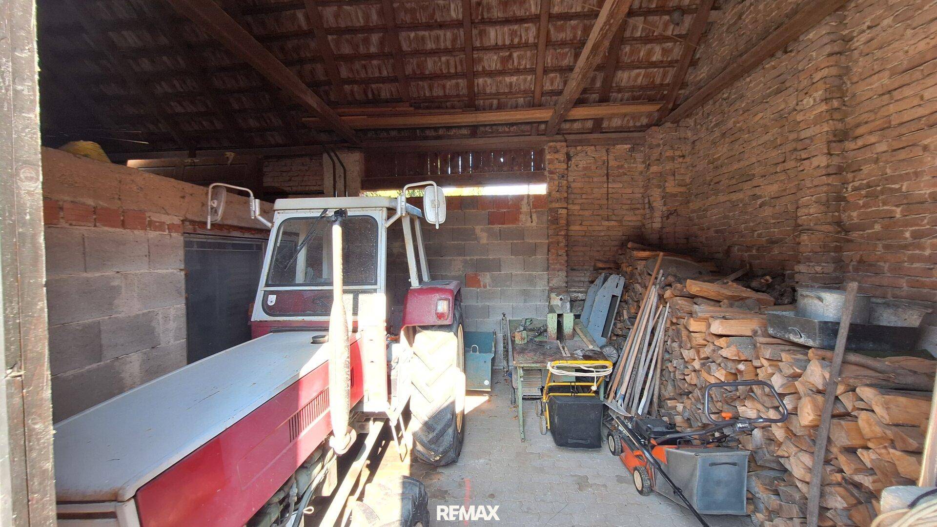 Geräumige Scheune oder Garage mit Traktor und Holzstapeln.