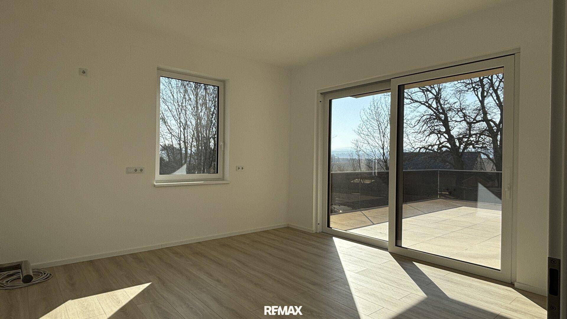 Helles Schlafzimmer mit Zugang zu einer großen Terrasse und weitem Ausblick.