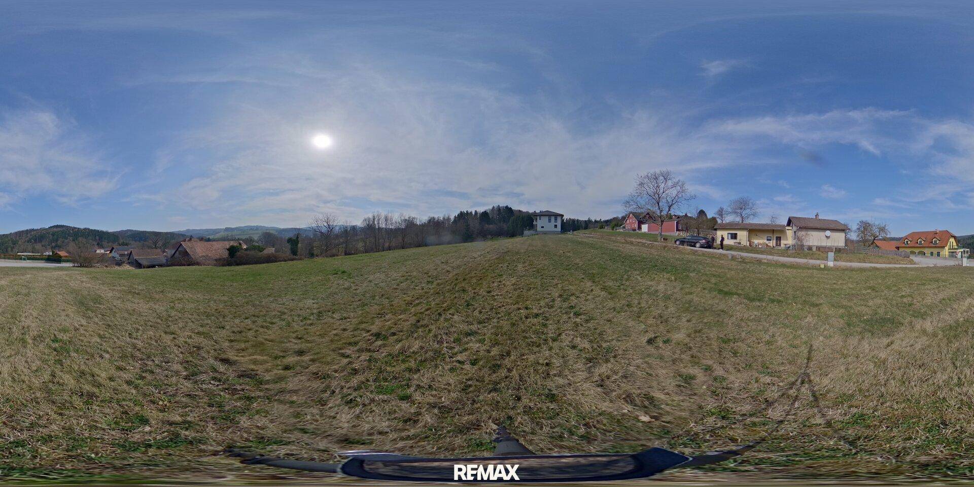 Panoramablick vom Baugrundstück über die weite Landschaft mit Häusern und sonnigem Himmel.