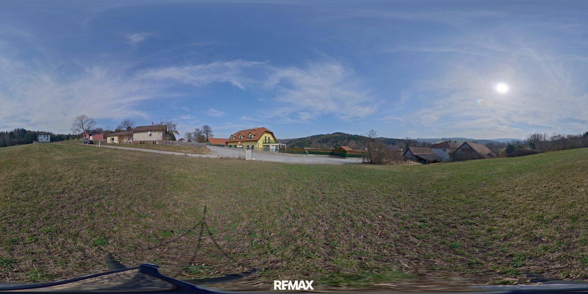 Weitläufiger Panoramablick vom Grundstück auf die ländliche Umgebung unter blauem Himmel.